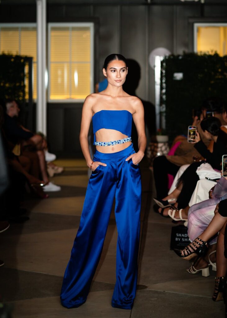 A confident model walks the runway in an elegant blue satin outfit, showcasing modern fashion trends.