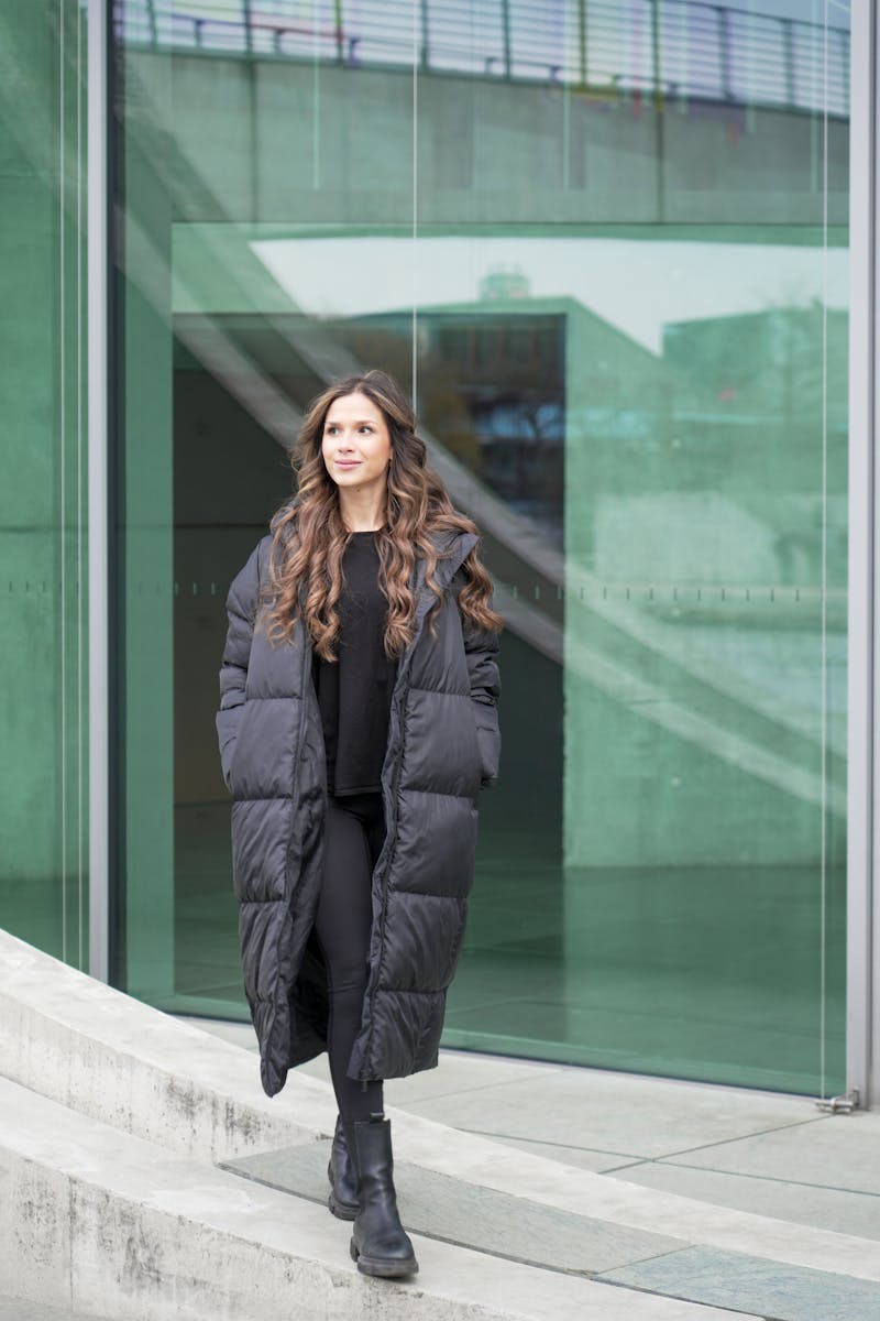 Fashionable woman in a puffer coat walking in Berlin cityscape.