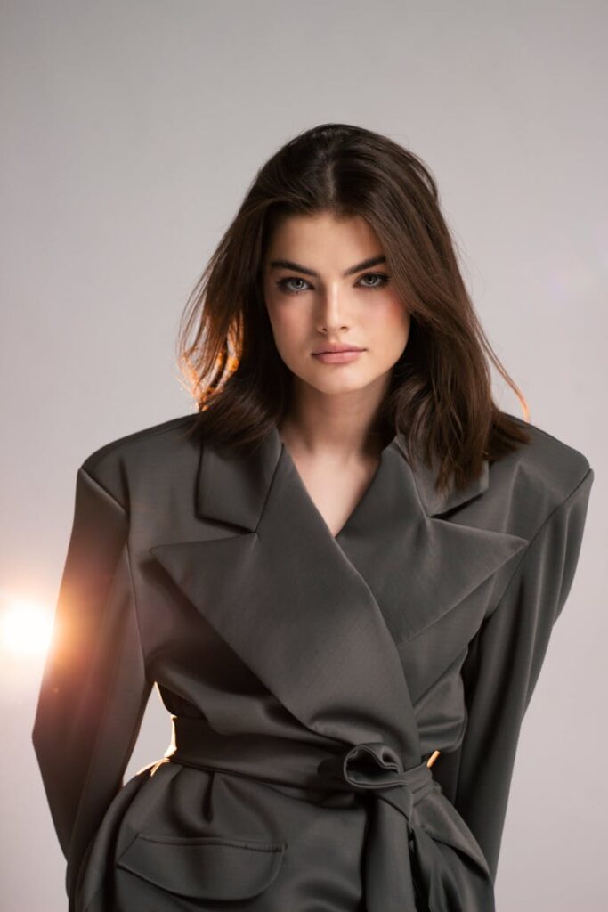 Portrait of a stylish brunette woman posing in a studio wearing an elegant blazer.