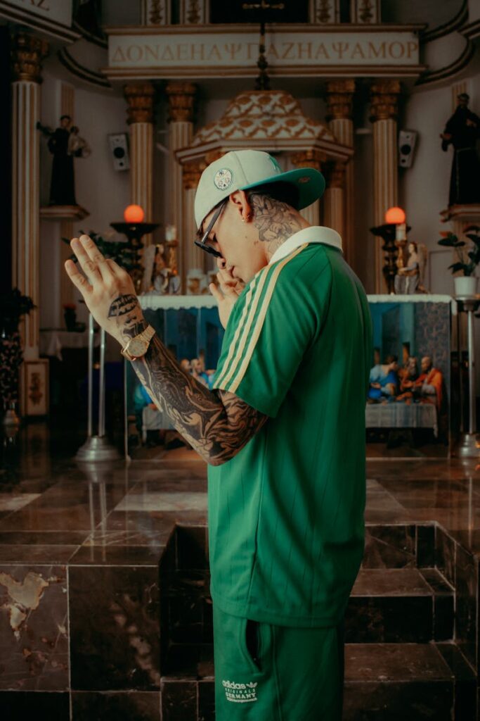 Tattooed man in green attire posing in a church interior.