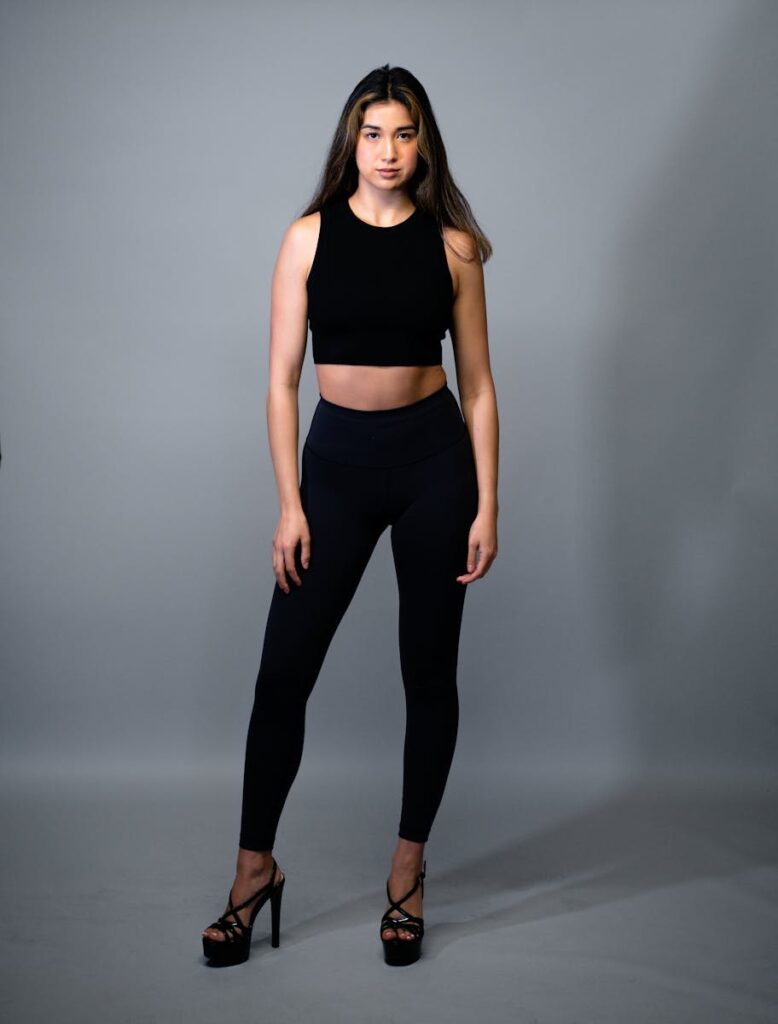 Elegant woman modeling in a studio with a gray background, showcasing fashion style.