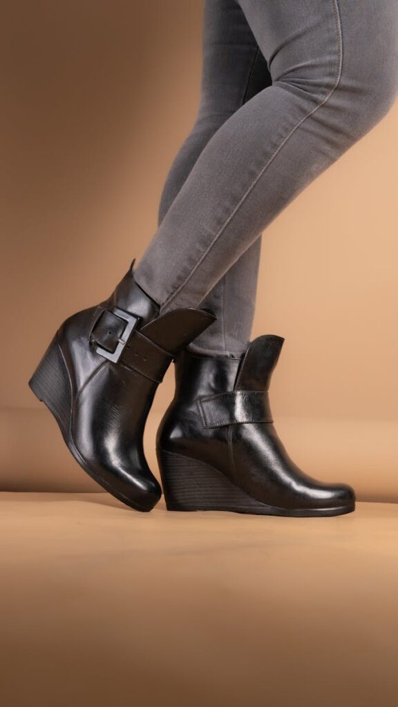Close-up shot of black leather wedge boots paired with grey pants, perfect for chic fashion.