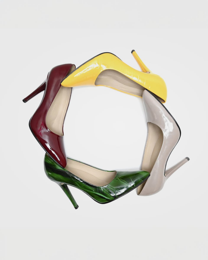 Four high heels in vibrant colors arranged in a circular pattern on a white background.