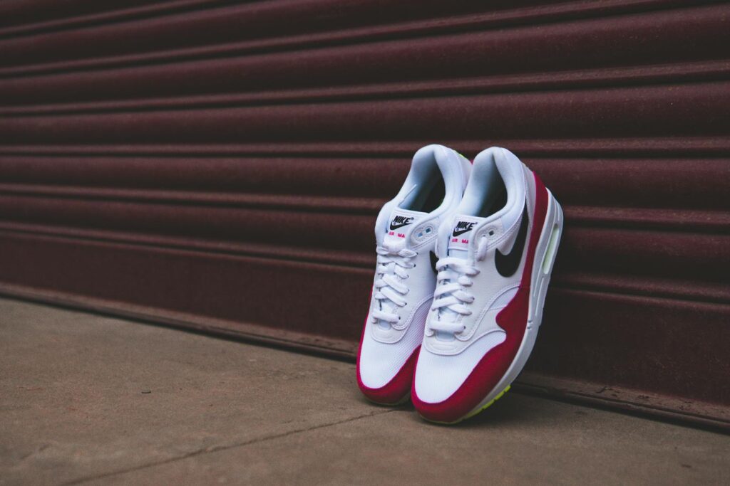 Stylish white and red sneakers leaning against a closed metal shutter, showcasing footwear design.
