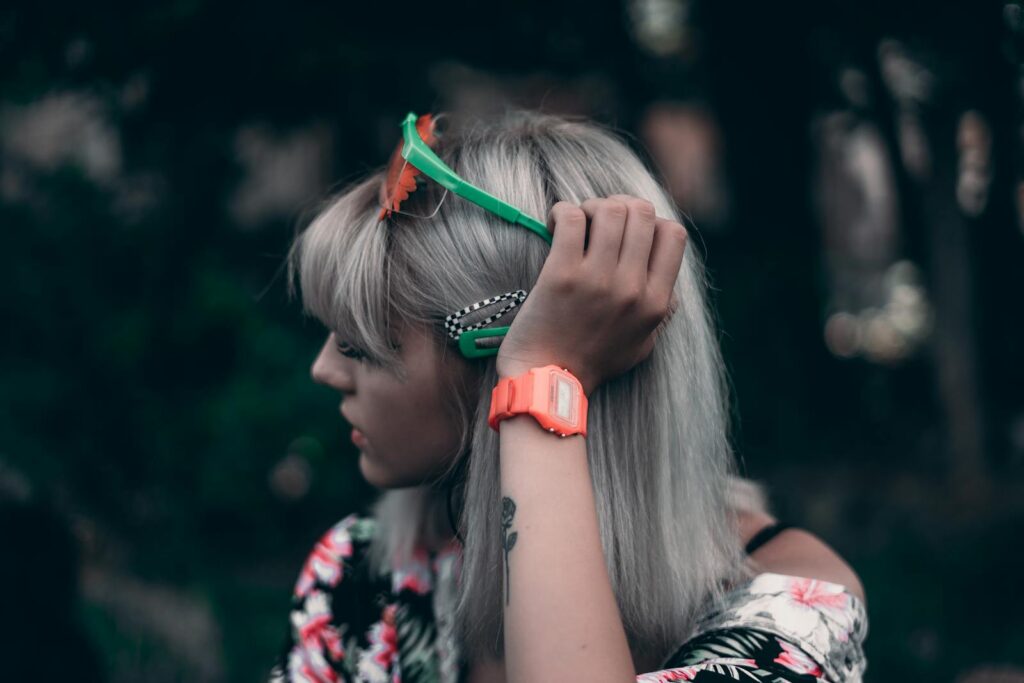 Portrait of a stylish woman with blonde hair adjusting sunglasses outdoors.