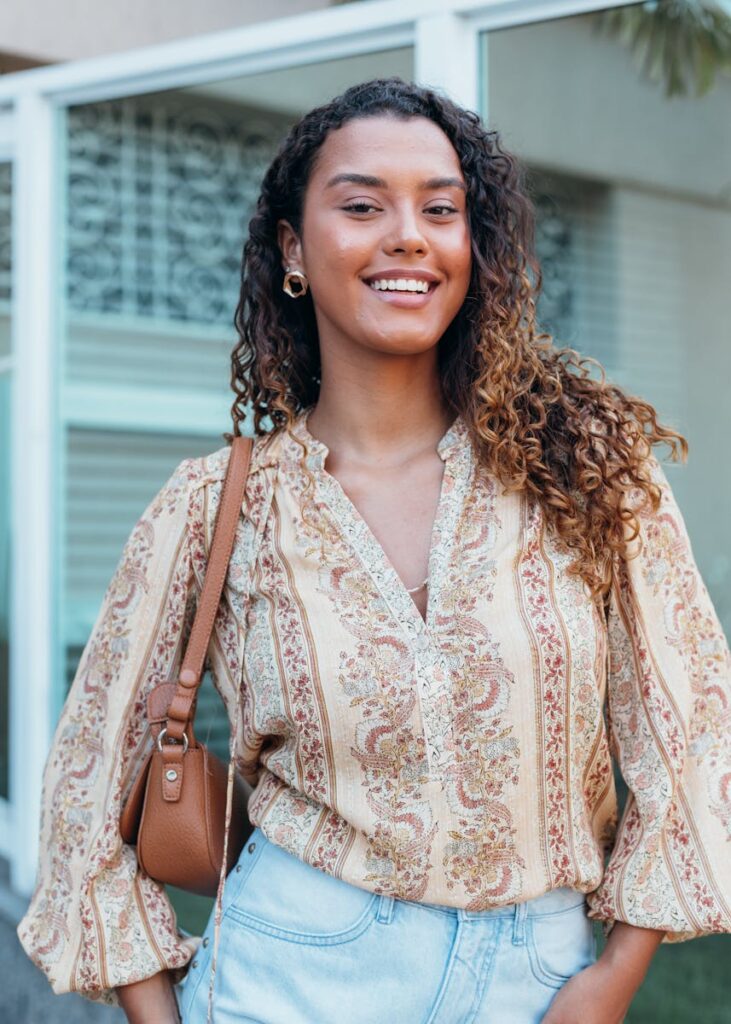 Young woman smiling outdoors in a bohemian blouse.