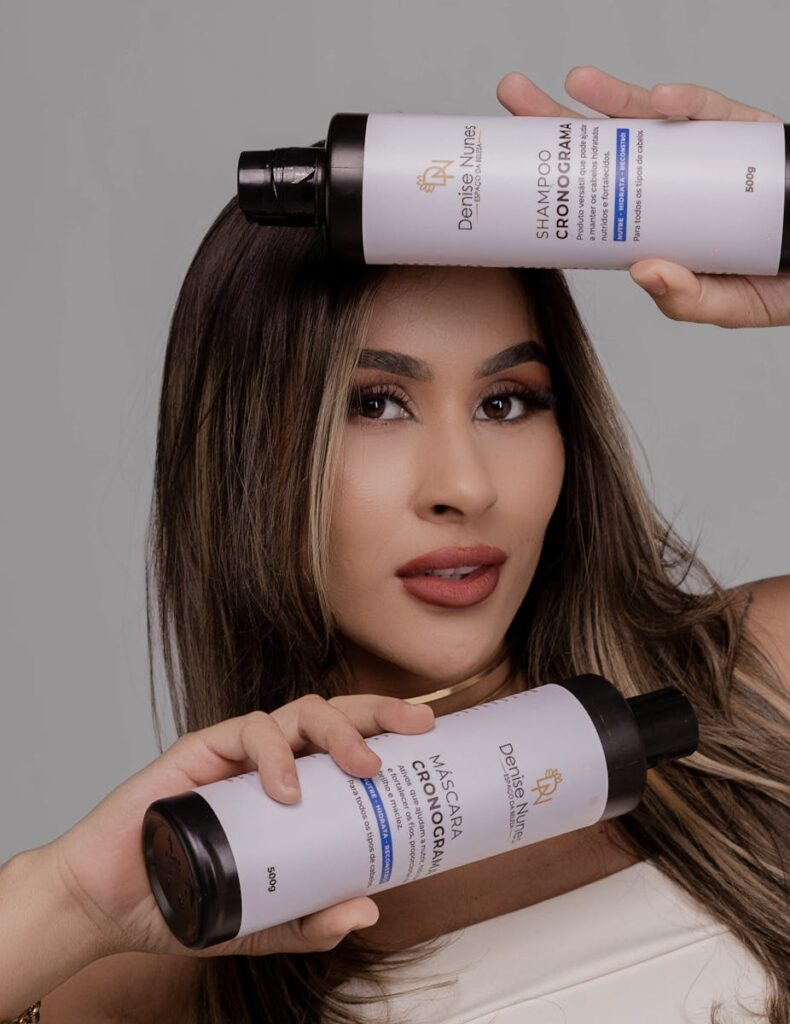 Woman holding shampoo and hair mask bottles, promoting hair care routine with a stylish pose.
