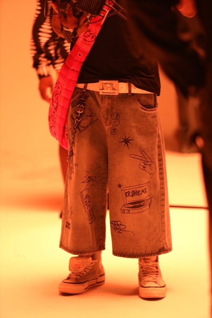 Stylish denim pants featuring unique graphic designs and urban accessories in warm lighting.