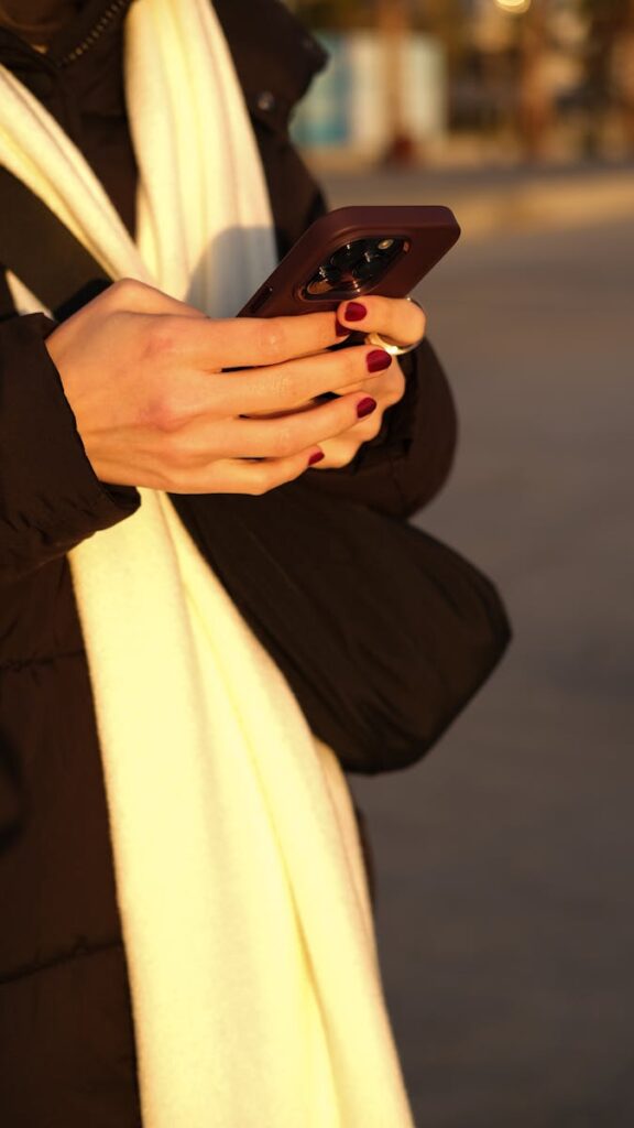 A woman with red nails using a smartphone outdoors in İstanbul.