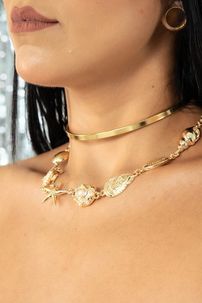 Close-up of a woman's neck adorned with intricate gold necklaces, showcasing elegant style.