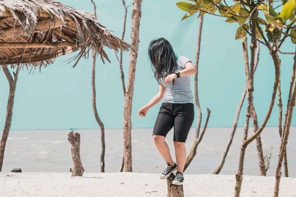 woman wearing gray shirt standing on trunk in front of sea