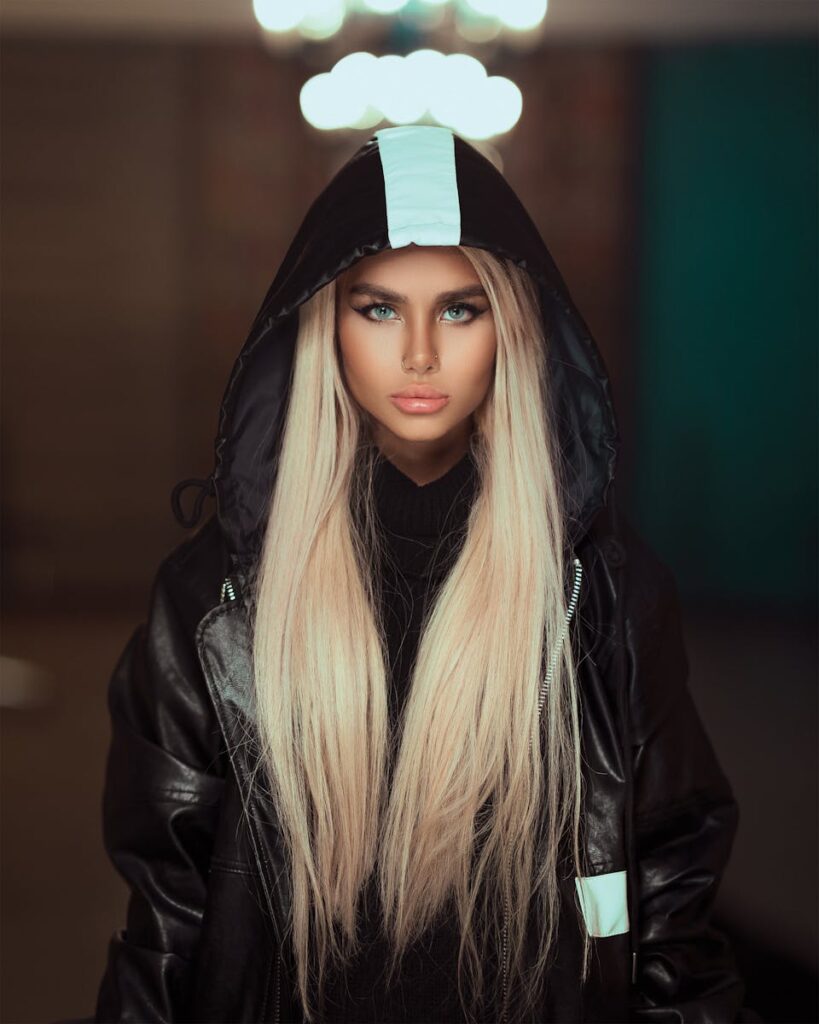Chic portrait of a woman with blonde hair and a leather hoodie in a stylish setting.