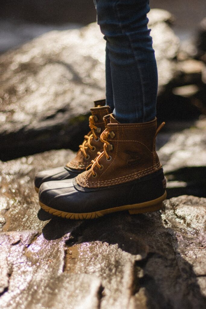 Close-up of a child's boots on a rocky surface under sunlight, showcasing rugged outdoor style.