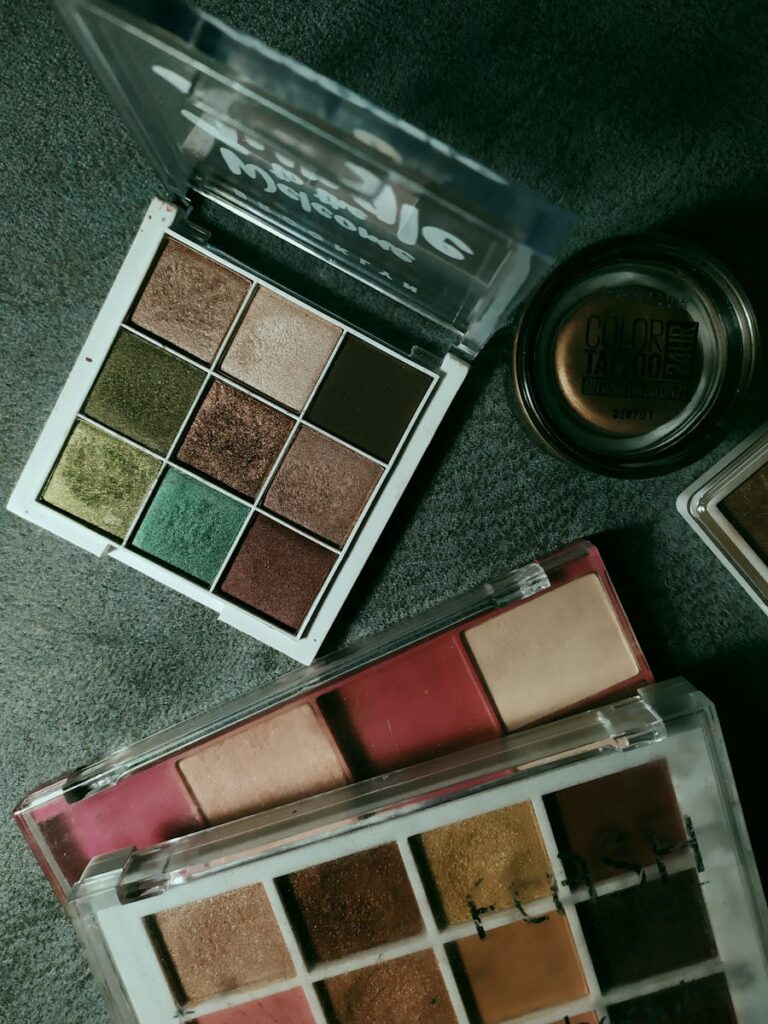 Top view of various makeup palettes showcasing vibrant eyeshadow colors on a textured gray surface.