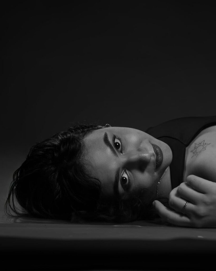 Artistic black and white portrait of a woman lying down with a thoughtful expression.
