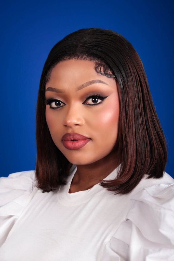 Stylish portrait of a woman against a blue background, emphasizing beauty and confidence.