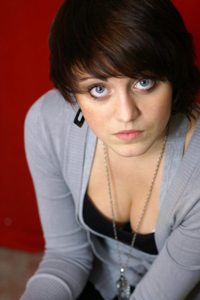 Close-up portrait of a woman with striking blue eyes against a red background.