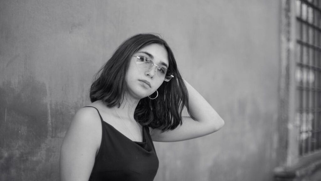 Stunning black and white portrait of a young woman posing thoughtfully against an urban backdrop.