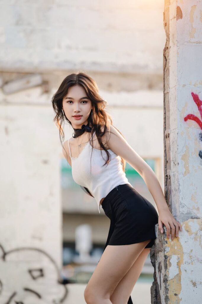 Young woman in casual attire posing in urban environment with sunlight.