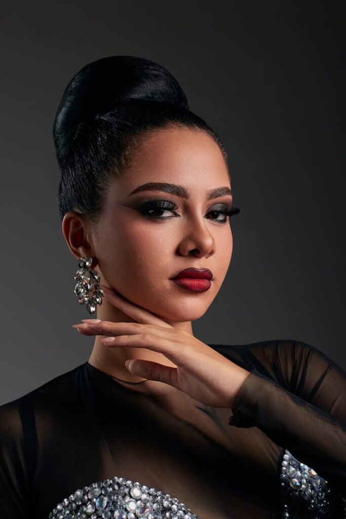 Elegant portrait of a woman with glamorous makeup, striking pose, and sparkling earrings.