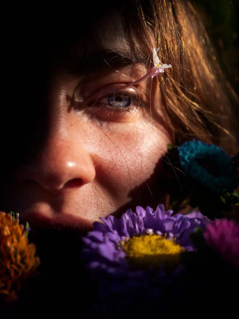 A captivating close-up portrait of a woman surrounded by colorful flowers, illuminated by natural light.
