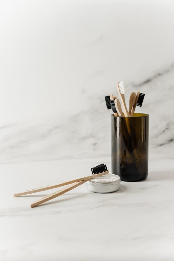 Sustainable bamboo toothbrushes in a glass cup with tooth powder, promoting zero waste hygiene.