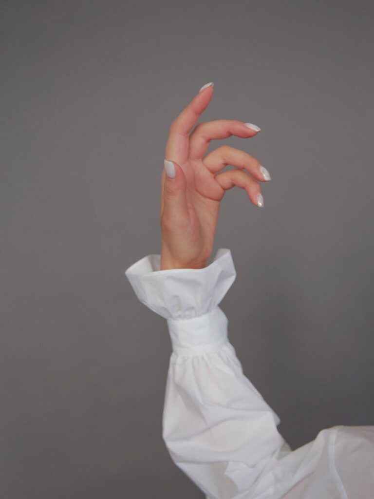 Close-up of an elegant hand gesture against a neutral grey backdrop.