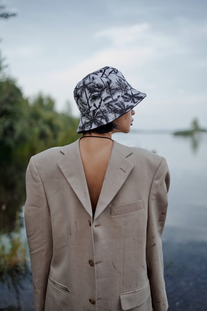 Back view of anonymous lady in ornamental panama hat and classic wear admiring river in countryside