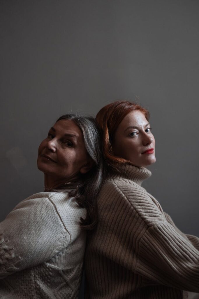 A touching portrait of two women back to back, expressing warmth and connection.