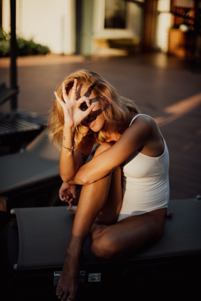 A carefree woman in a white swimsuit poses outdoors, embodying relaxation and joy.