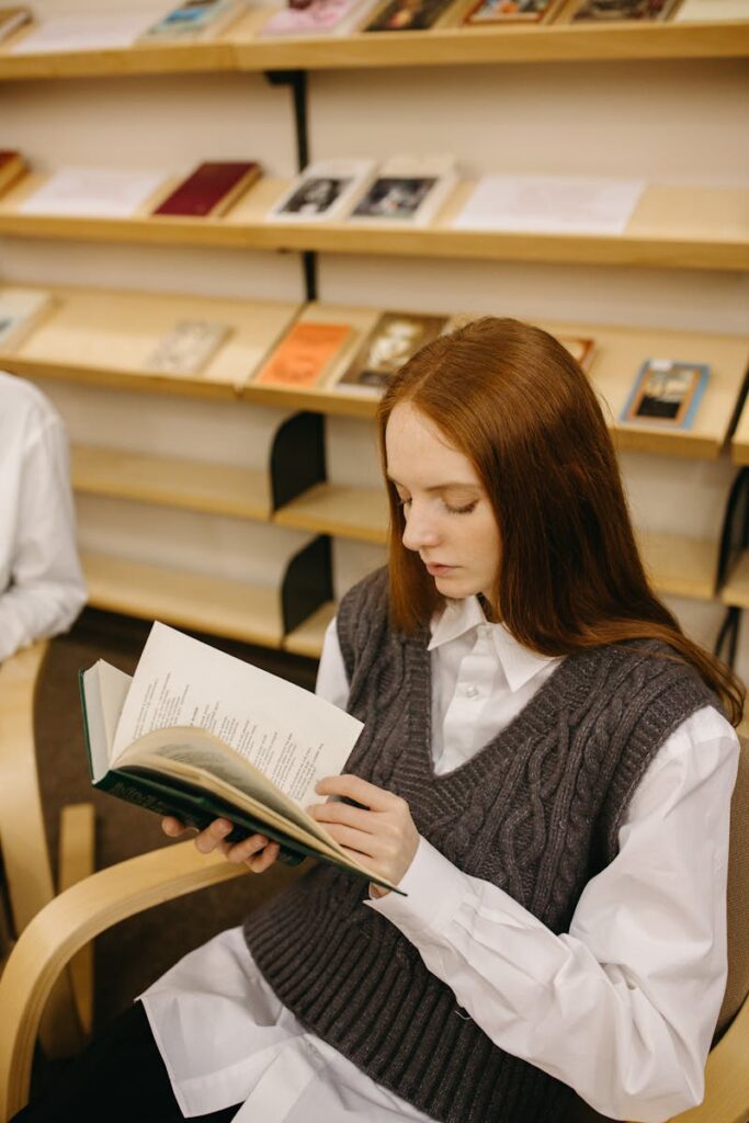 Young woman reading a book in a library, capturing a peaceful and focused atmosphere.