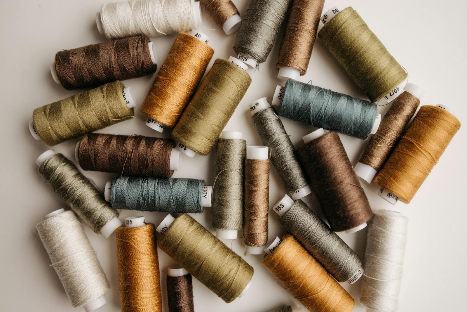 A collection of multicolored sewing threads arranged on a white surface, perfect for textile or crafting projects.