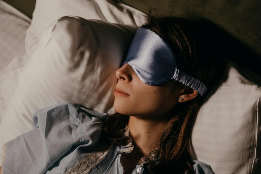 A woman peacefully sleeping indoors wearing a silk eye mask, capturing calm and relaxation.