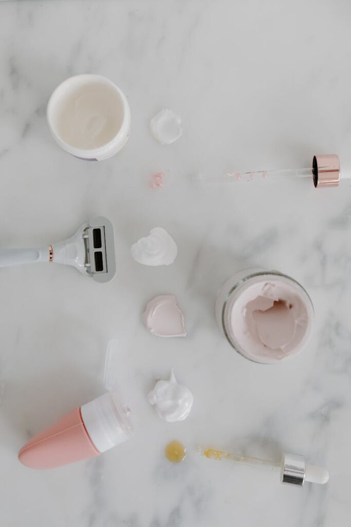 Aesthetic flat lay showcasing skincare and shaving essentials with a minimalist design on a marble surface.