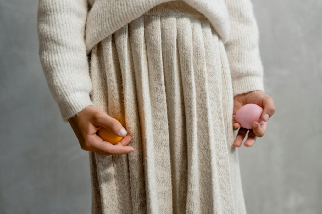 A person holding colorful Easter eggs in a cozy knit outfit. Perfect for holiday themes.