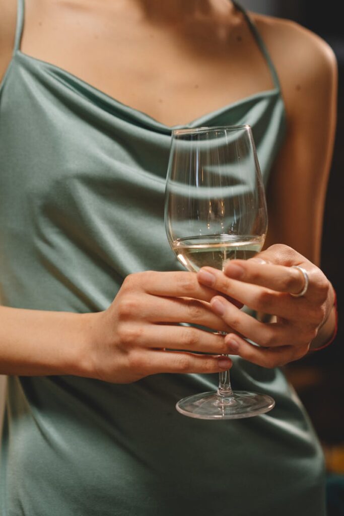 Close-up of a woman in a silk dress holding a wine glass, exuding sophistication and elegance.