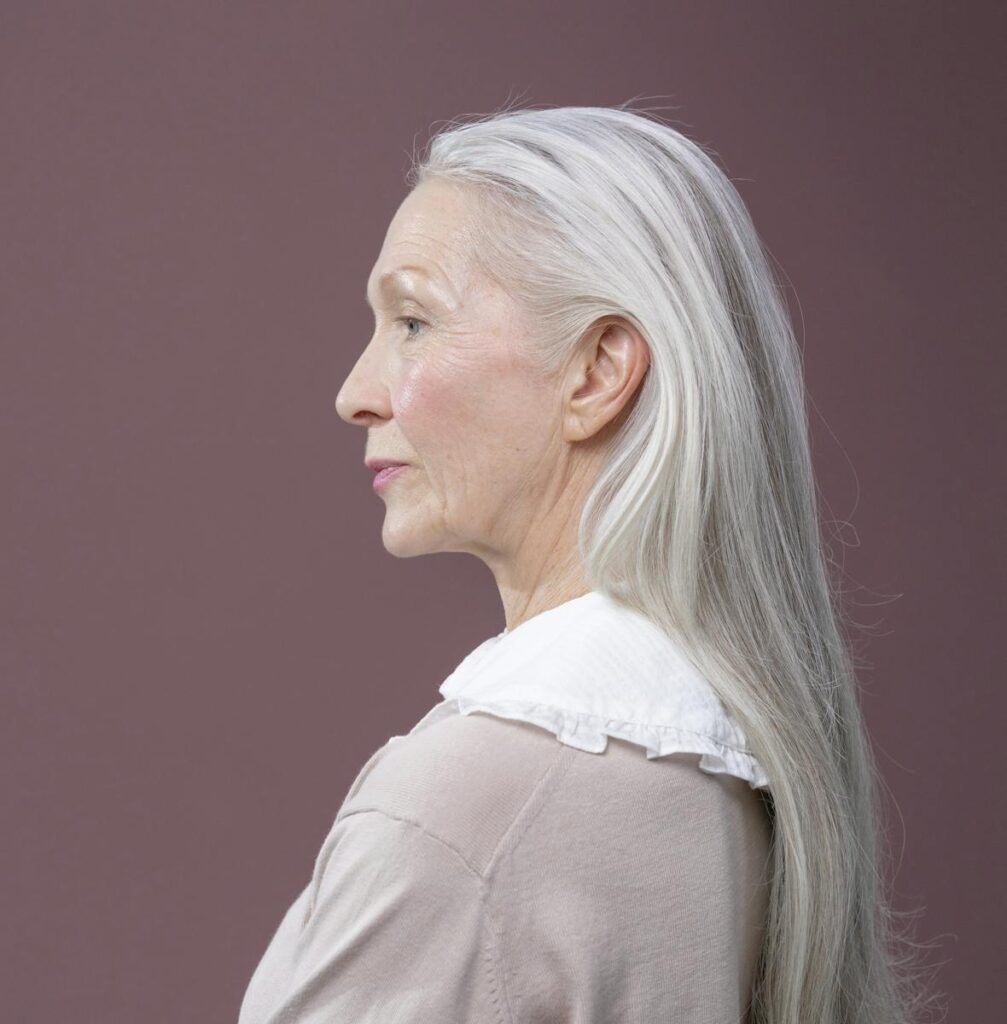Portrait of a senior woman with long gray hair and a thoughtful expression, profile view.
