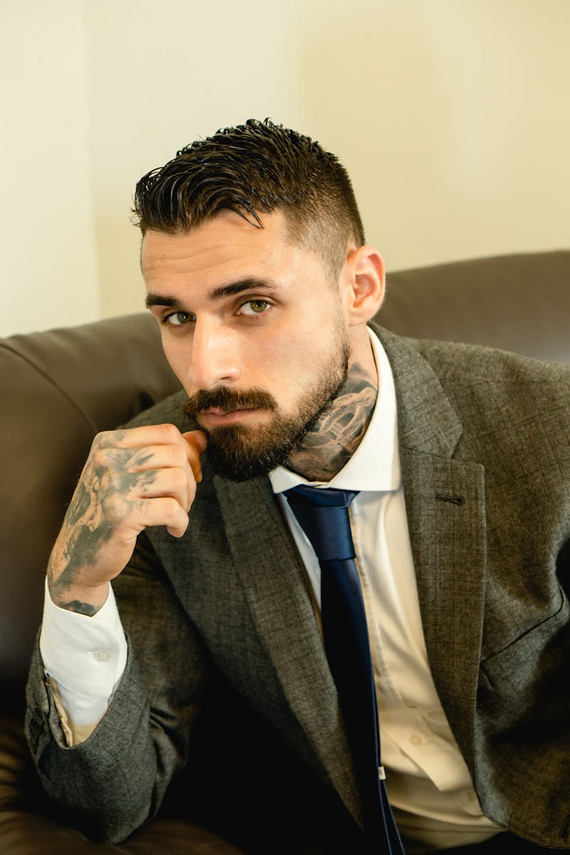 Elegant portrait of a bearded man with tattoos wearing a suit and tie.