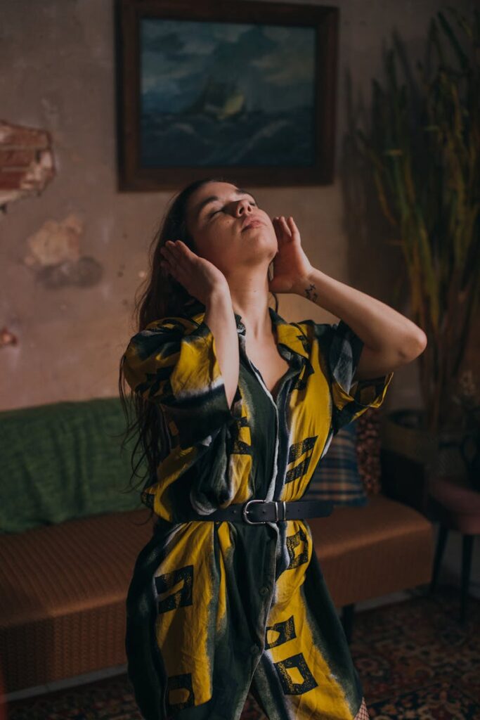 Stylish woman in a colorful dress posing in a cozy indoor setting with artwork.