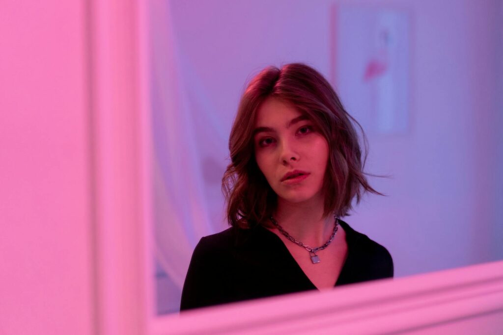 Portrait of a woman with a bob haircut in a room with pink lighting, creating a moody vibe.