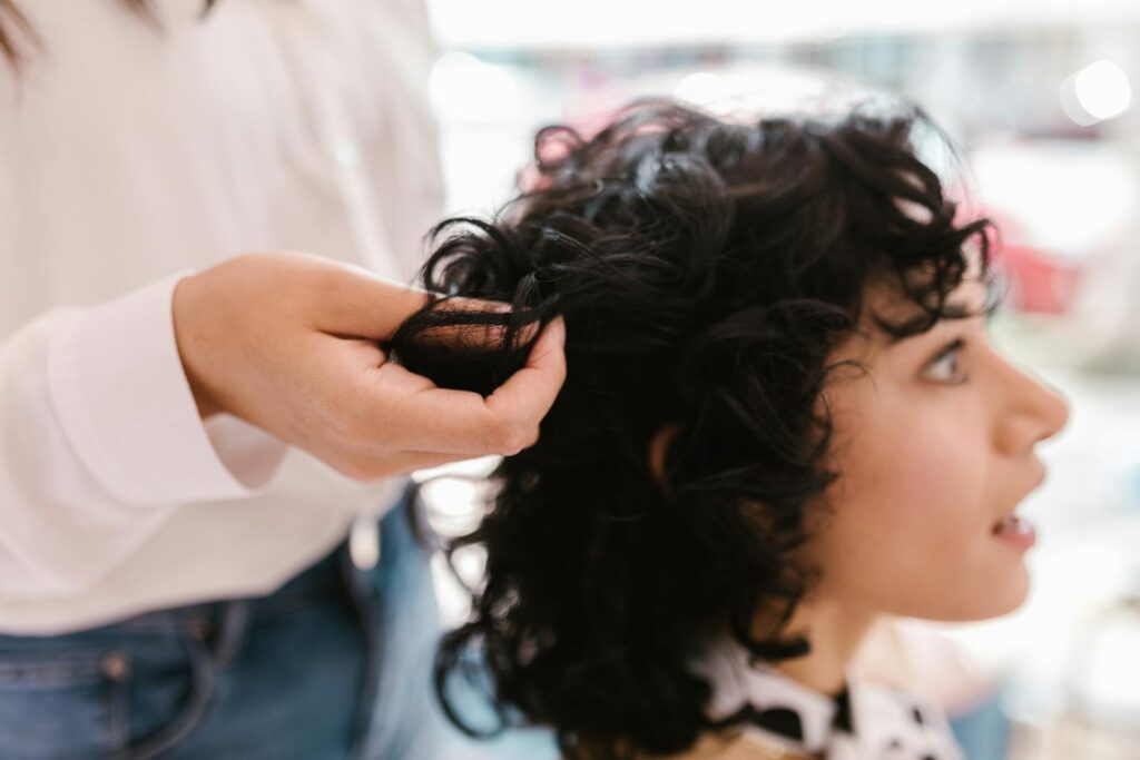 Close-up of a woman getting her hair styled indoors, showcasing self-care and salon expertise.