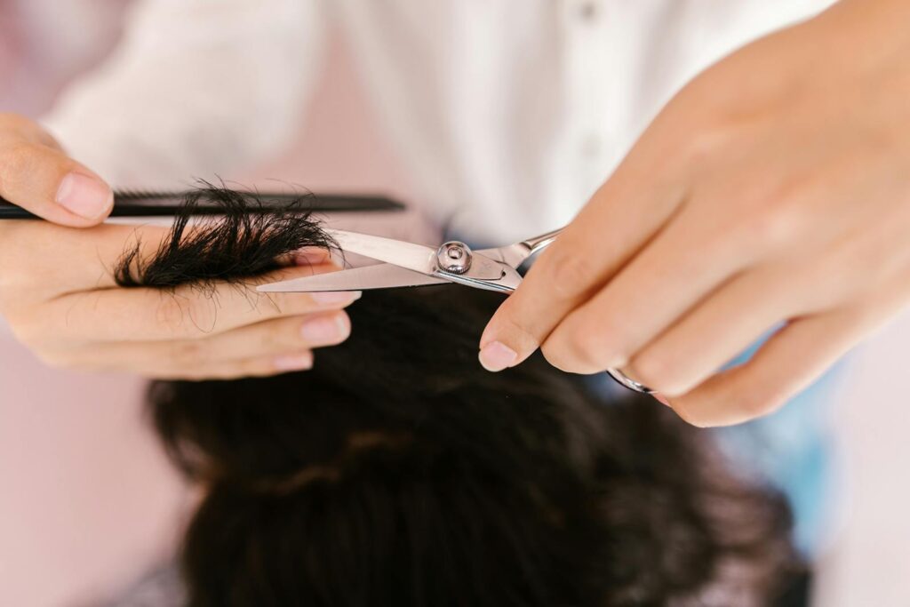 Close-up of hands cutting hair with scissors at a salon.