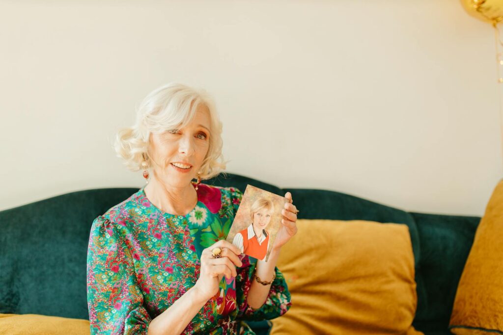 A cheerful senior woman holding a vintage photo, recalling fond memories.