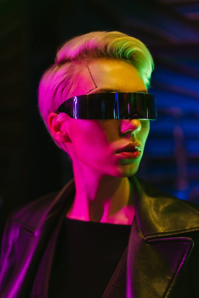 Striking portrait of a woman in cyberpunk attire with futuristic eyewear and neon lighting.