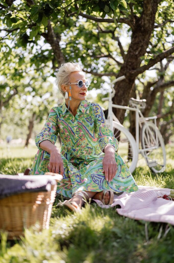 Stylish senior woman in printed dress relaxing in a sunny park.