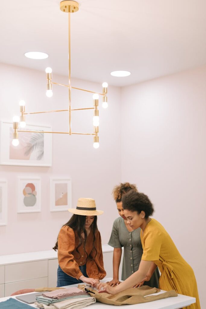 Three women in a modern office setting discuss fashion planning, showcasing teamwork and creativity.