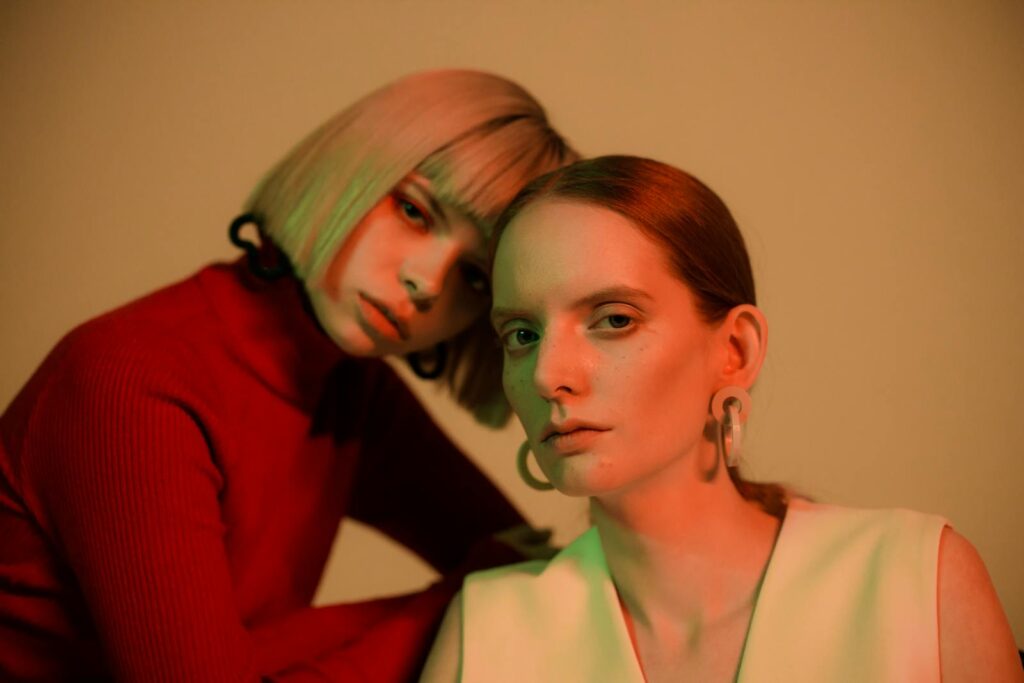 Close-up artistic portrait of two women with creative lighting and modern styling.