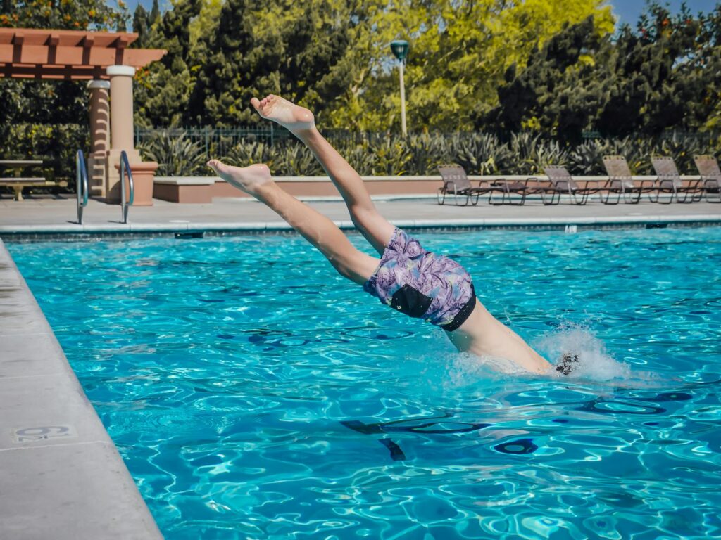 Person diving into a swimming pool, capturing summer fun and leisure outdoors.