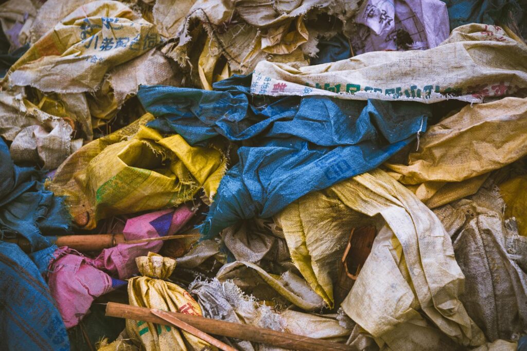 A vibrant mix of discarded textile bags in a recycling pile, showcasing the importance of waste management.