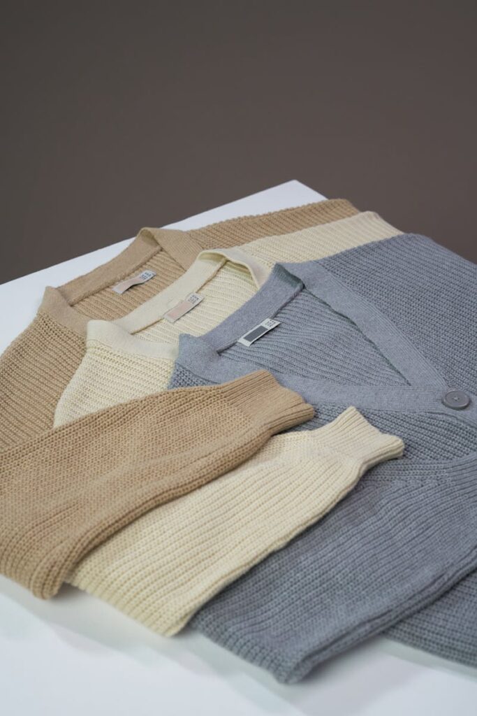 A simple flat lay of neutral-colored cardigan sweaters on a table.